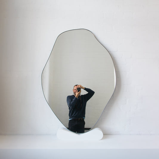 Modern freeform organic shaped mirror with a minimalist brass frame with a bronze patina finish