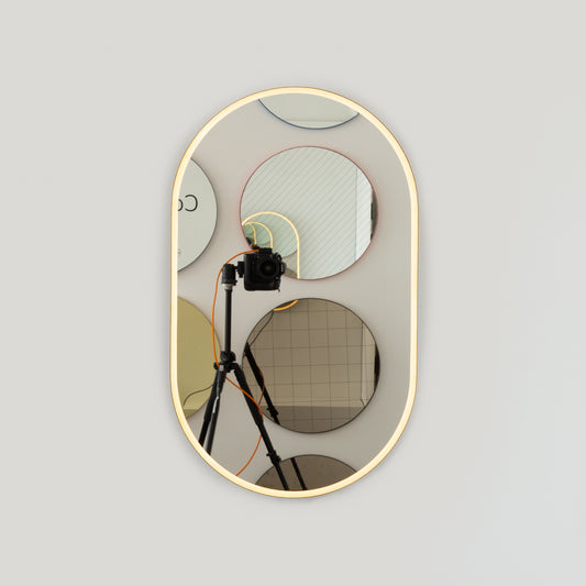 Modern pill shaped mirror with an elegant bronze patina brass frame and front illumination