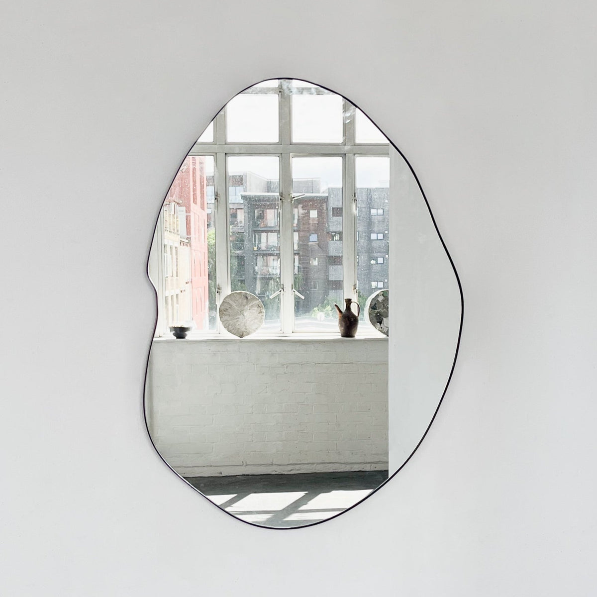 Modern freeform organic shaped mirror with a black powder coated aluminium frame
