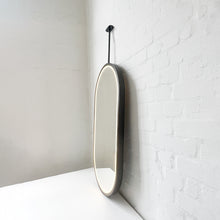Modern front illuminated Capsula™ ceiling suspended pill shaped mirror with a black powder coated full frame.
