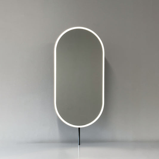 Modern front illuminated countertop pill shaped mirror with a blackened stainless steel frame
