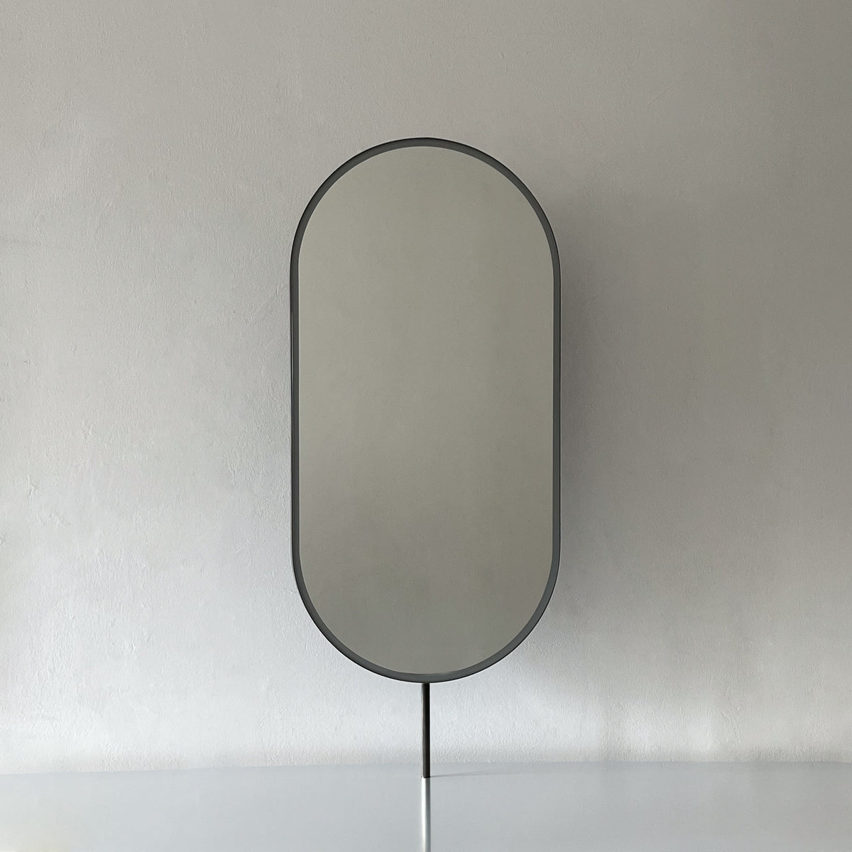 Modern countertop pill shaped mirror with a blackened stainless steel frame