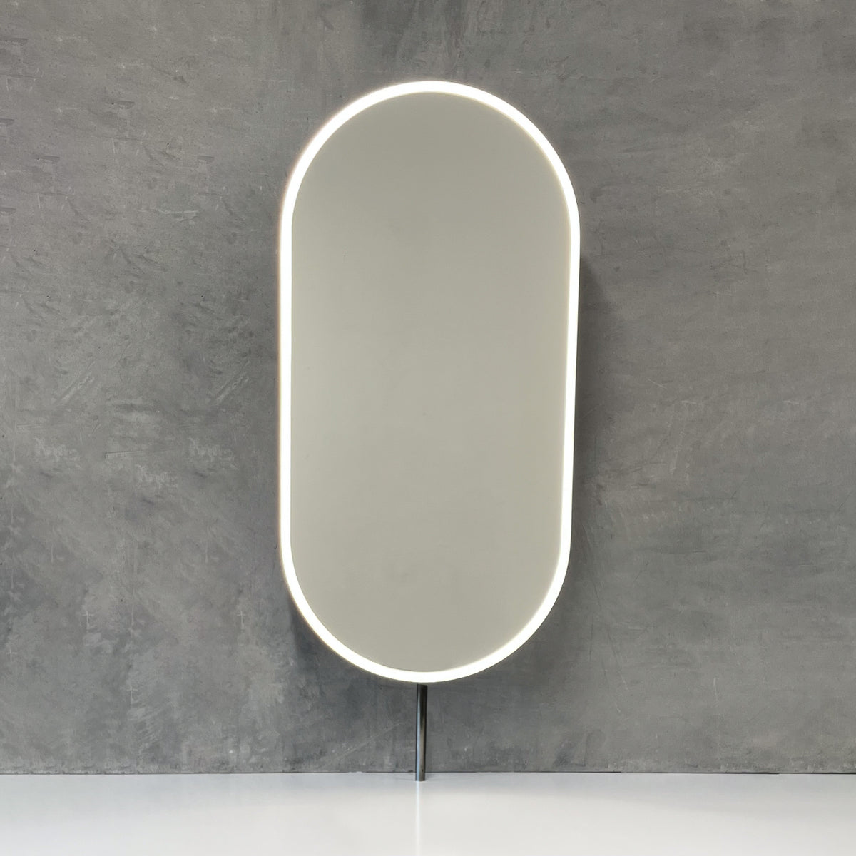 Modern front illuminated countertop pill shaped mirror with a blackened stainless steel frame