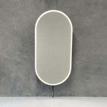 Modern front illuminated countertop pill shaped mirror with a blackened stainless steel frame