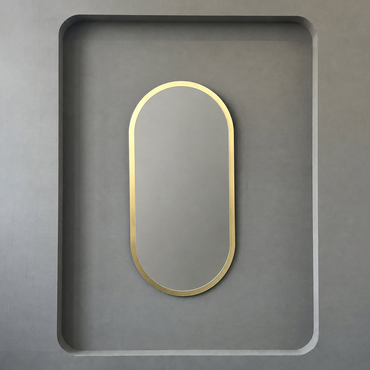 Modern Capsula™ pill shaped mirror with an architectural TIPO™ frame with brushed brass finish