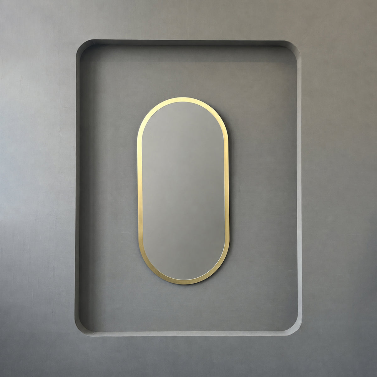 Modern Capsula™ pill shaped mirror with an architectural TIPO™ frame with brushed brass finish