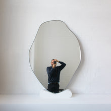Modern freeform organic shaped mirror with a minimalist brass frame with a bronze patina finish