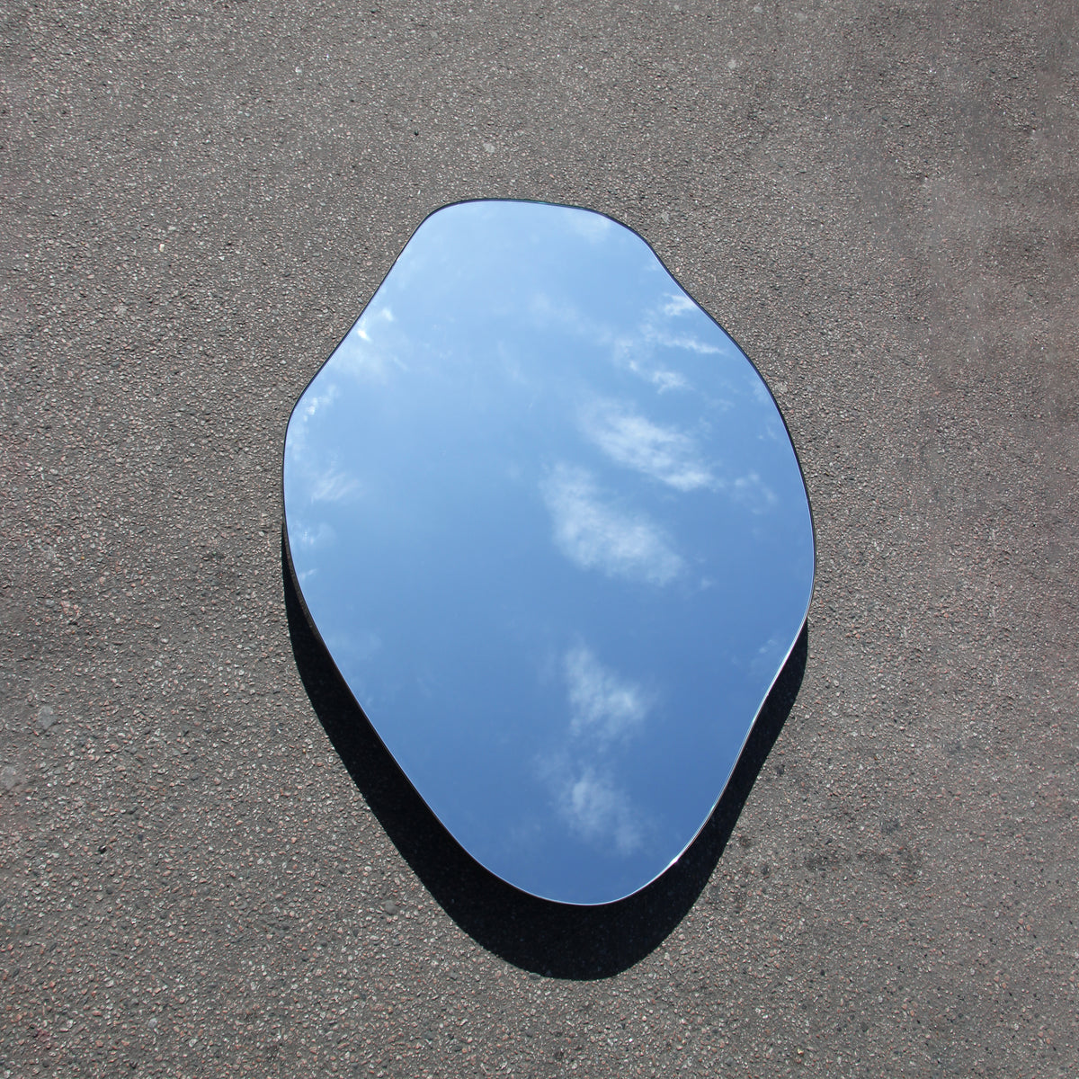 Modern freeform organic shaped mirror with a minimalist brass frame with a bronze patina finish