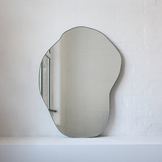 Modern freeform organic shaped mirror with a minimalist brass frame with a bronze patina finish