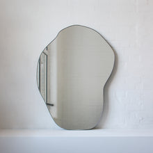 Modern freeform organic shaped mirror with a minimalist brass frame with a bronze patina finish