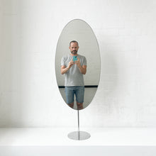 Countertop attached oval mirror with a modern stainless steel frame