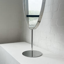 Countertop attached oval mirror with a modern stainless steel frame