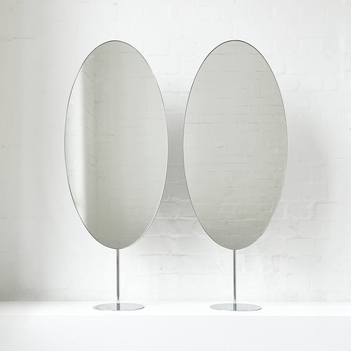 Countertop attached oval mirrors with a modern stainless steel frame