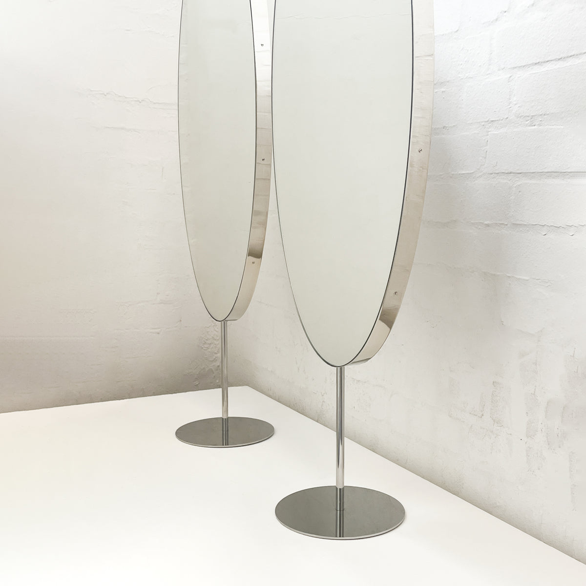 Countertop attached oval mirrors with a modern stainless steel frame