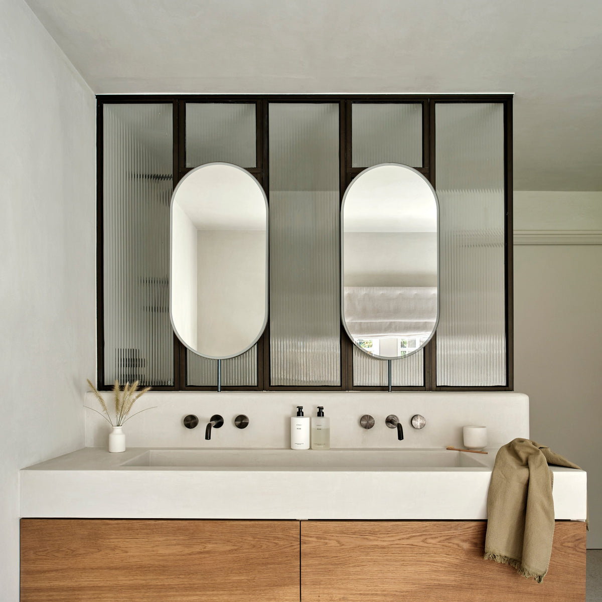 Set of two modern front illuminated Capsula™ countertop pill shaped mirrors with a minimalist blackened stainless steel frame