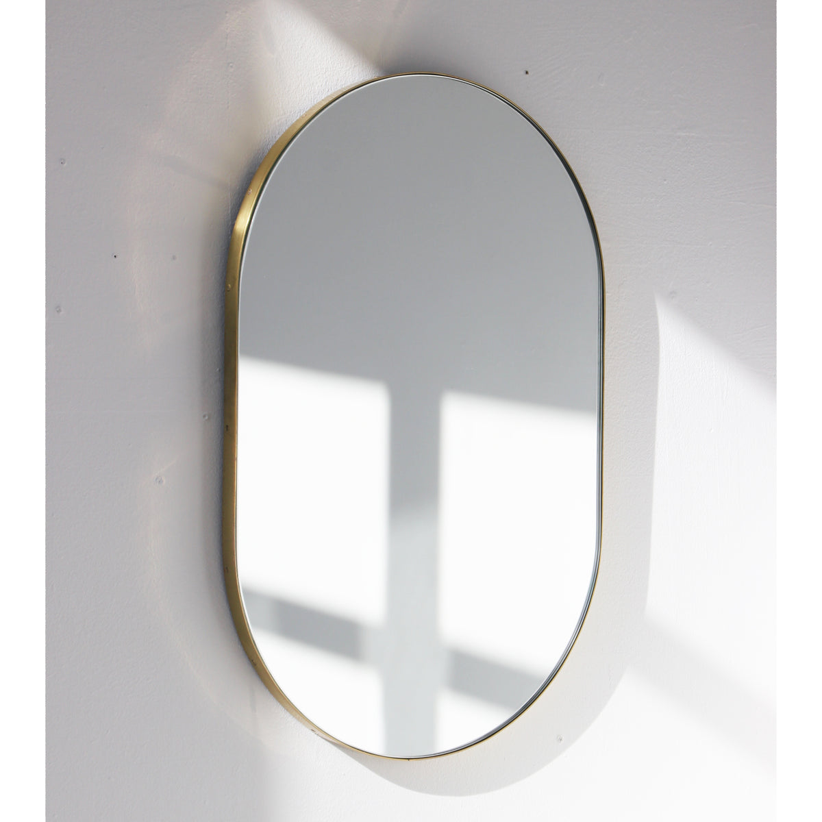 Capsula™ Suspended Capsule shaped Bathroom Mirror with a Brushed Brass Frame