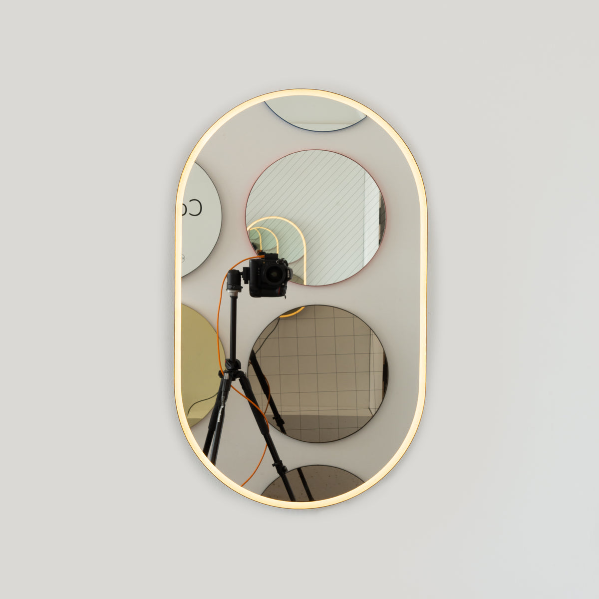 Modern pill shaped mirror with an elegant bronze patina brass frame and front illumination