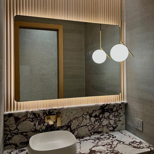 Contemporary back illuminated rectangular mirror with rounded edges and a solid brushed brass frame